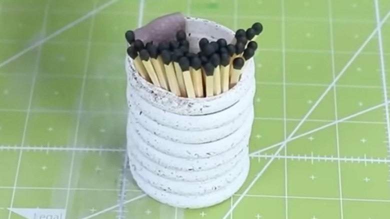 İçinde kibrit çöpleri bulunan üst üste yığılmış duş perdesi halkalarından yapılmış DIY saklama kabı