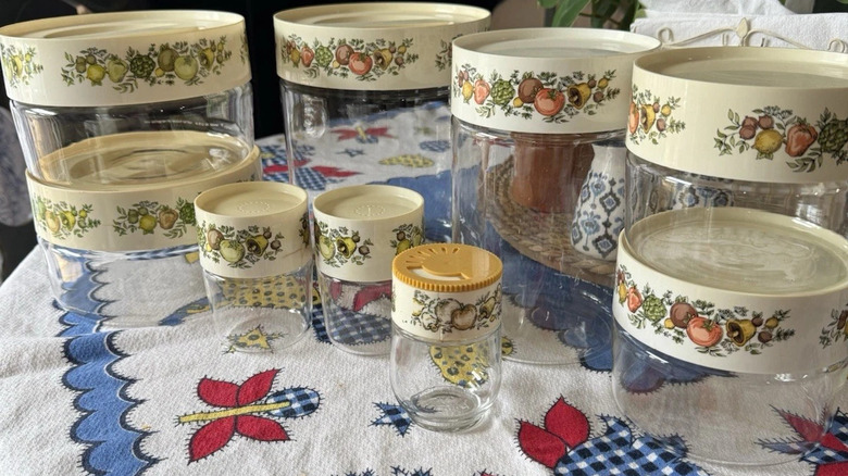 Desenli bir masa örtüsüyle birlikte bir masanın üzerinde düzenlenmiş Pyrex Spice O'Life cam kutulardan oluşan bir koleksiyon.