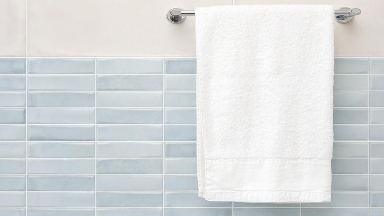 Banyoda duvar rayına asılı beyaz tüylü banyo havlusu