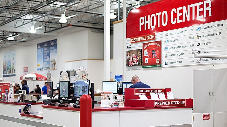 Bilgisayarda çalışan bir adamın olduğu Costco fotoğraf merkezi