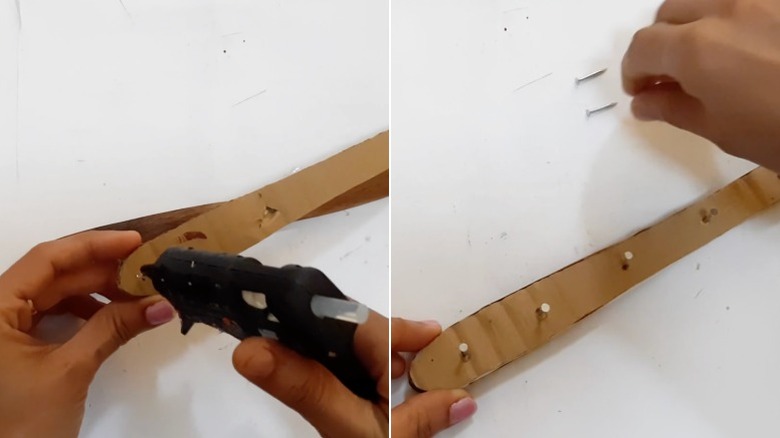 Eller bir parça kartonu ve birkaç çiviyi tahta bir spatulanın sapına yapıştırır.