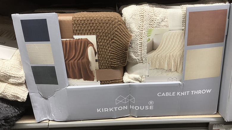 Kirkton House etiketli bir kutuda beyaz ve kahverengi renkte örgü atkılar.