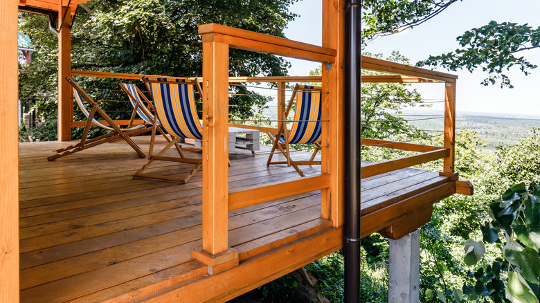 Yeşillikler arasında şezlong ve masanın bulunduğu balkon.