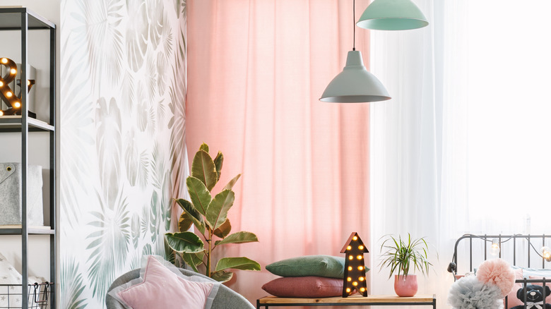 Pembe perdeli ve yeşil-beyaz desenli duvar kağıdına sahip bir yatak odası.