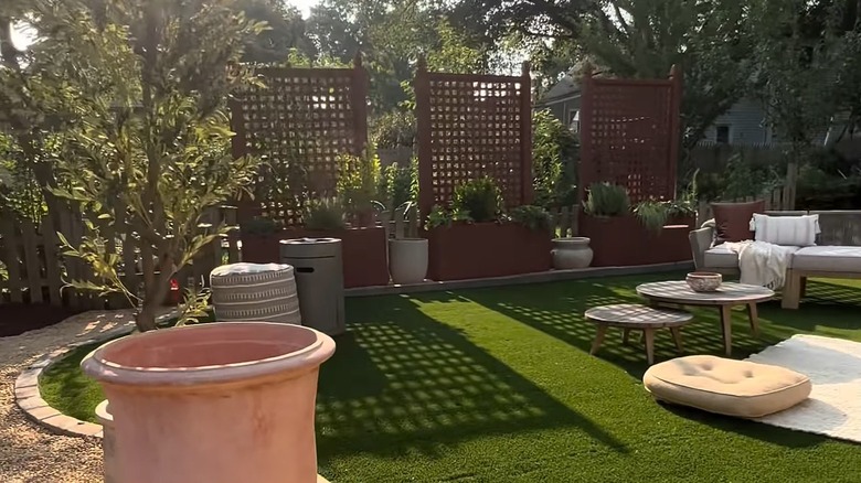 Kafes mahremiyet saksılarının bulunduğu peyzajlı bir arka bahçe.