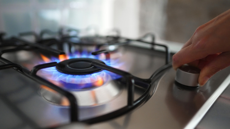 Kadın ocaktaki gaz ocağını açıyor.
