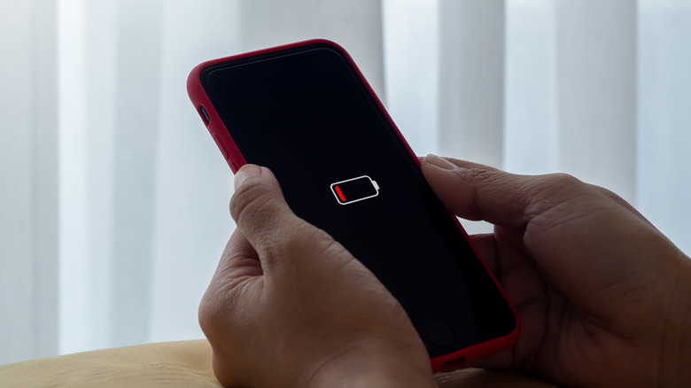 Düşük pil bildirimi olan bir akıllı telefonu tutan kişi