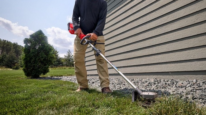 Milwaukee 3016-21ST kullanarak çimleri kesen bir kişi
